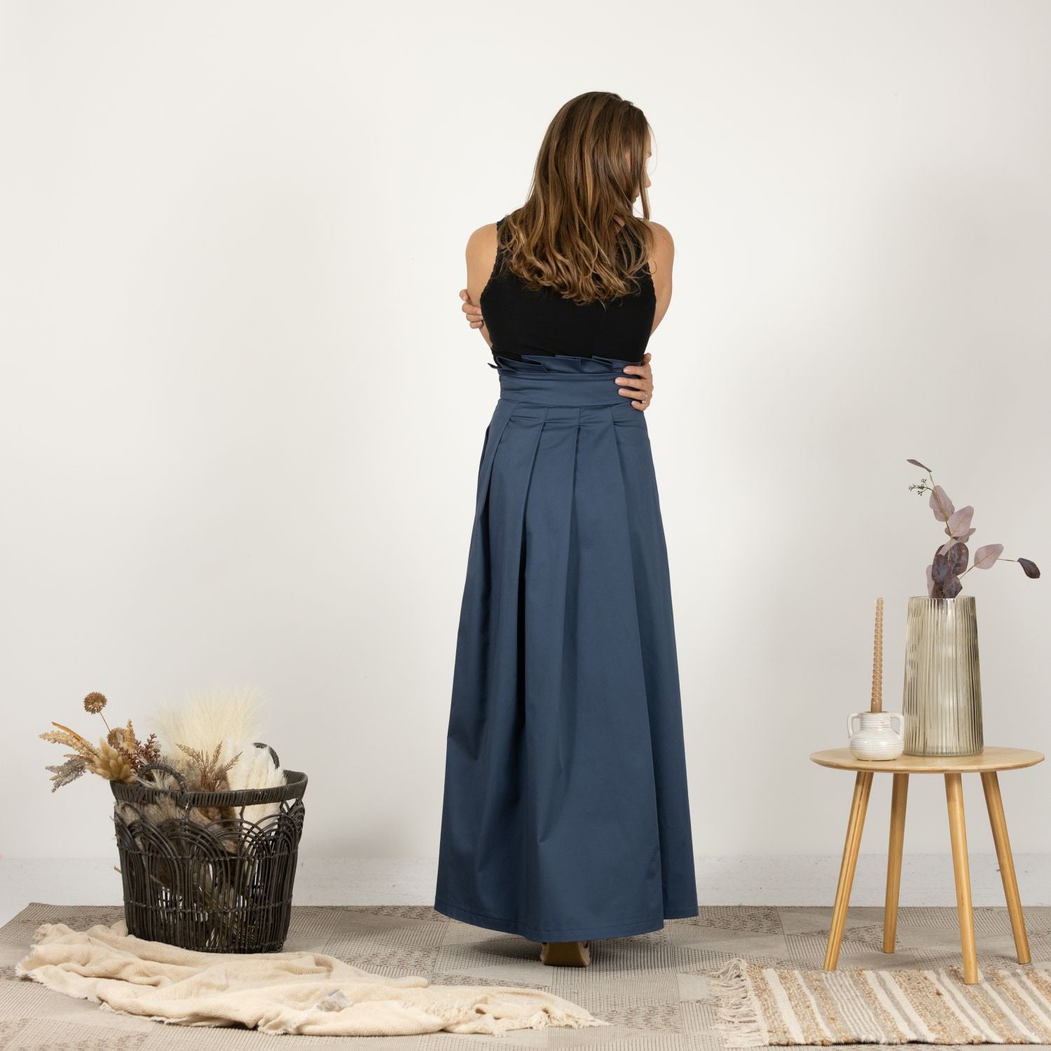 Back view of model in the High-Rise Pleated Cotton Skirt, showing the full length and pleated design.