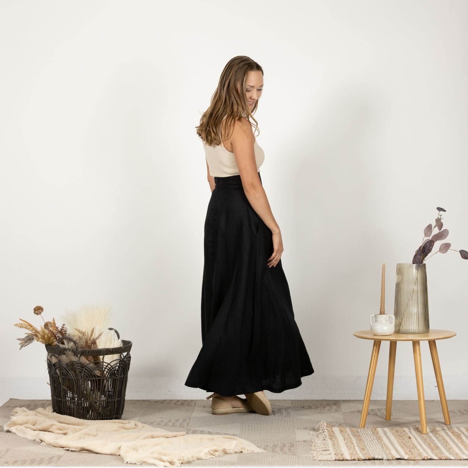 Side view of the Black Minimalist High Waist Linen Maxi Skirt, showcasing the smooth drape of the Italian linen fabric and the flattering high waist silhouette.