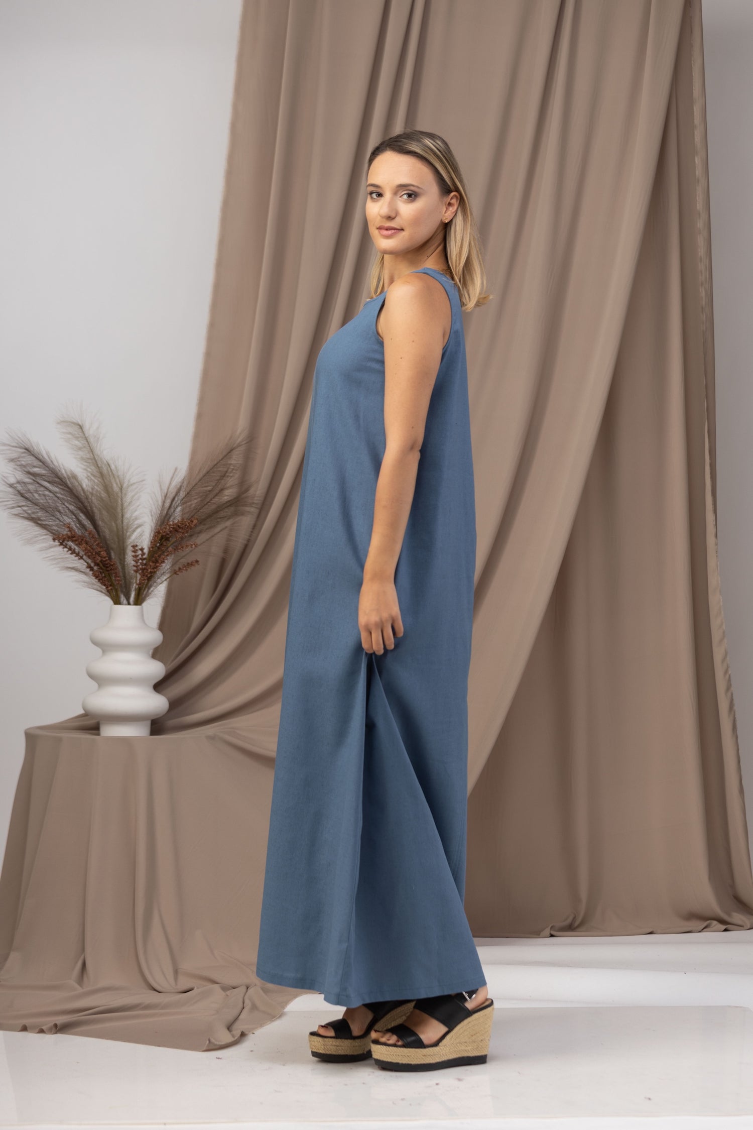 Model showcasing Minimalist Linen Maxi Dress in front of a beach background - from NikkaPlace | Effortless fashion for easy living